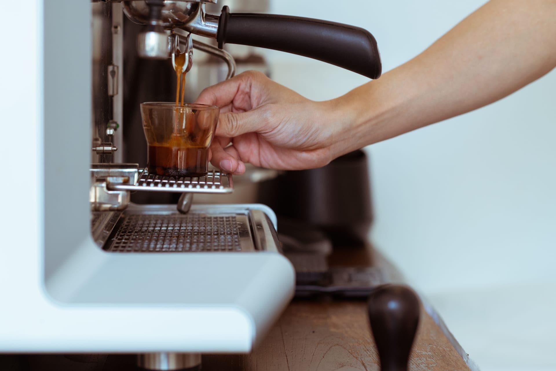 Espresso pouring from a portafilter into a cup, warm light on a dark background