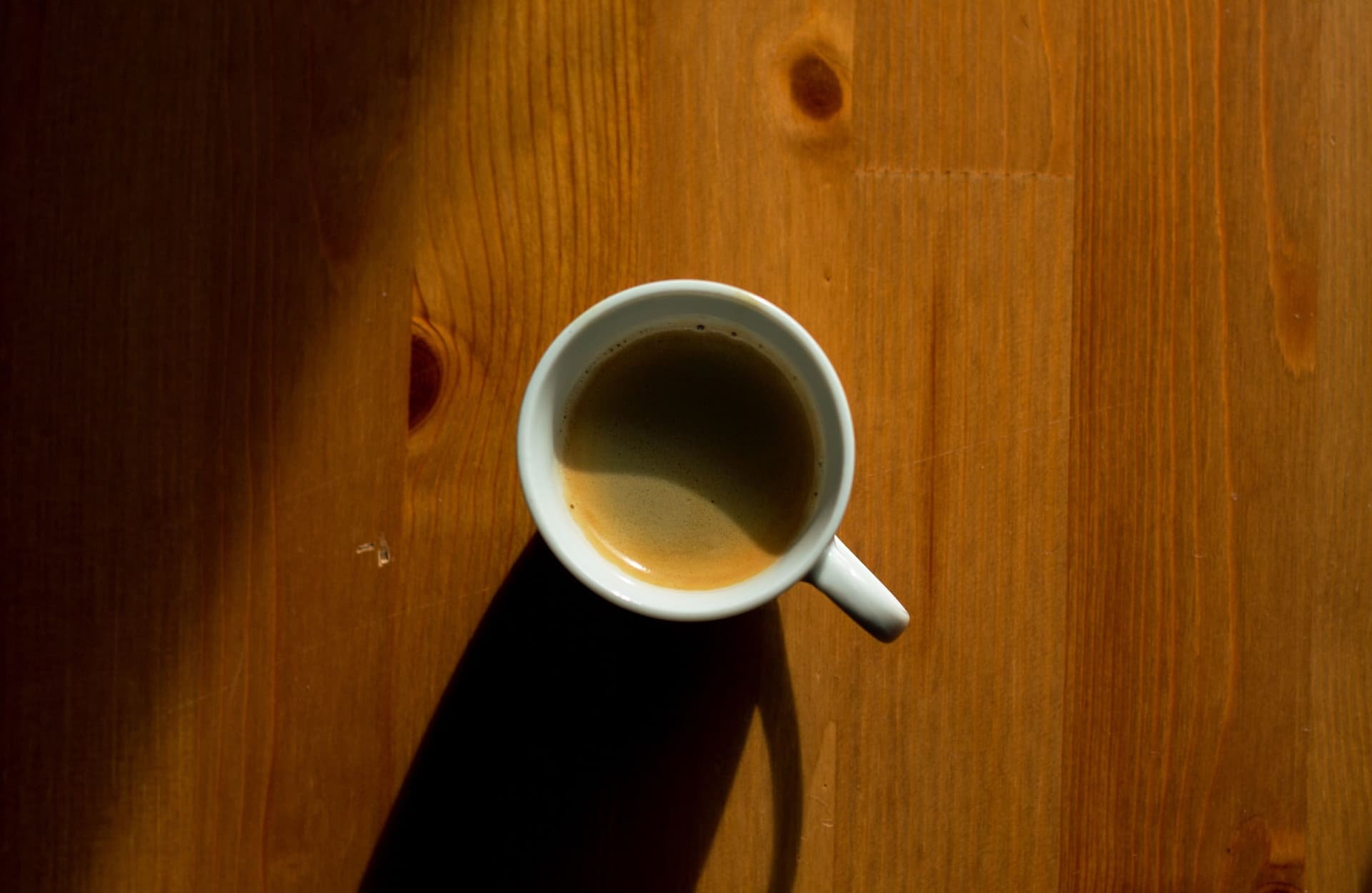 A cup of espresso and a cup of coffee side by side on a dark surface